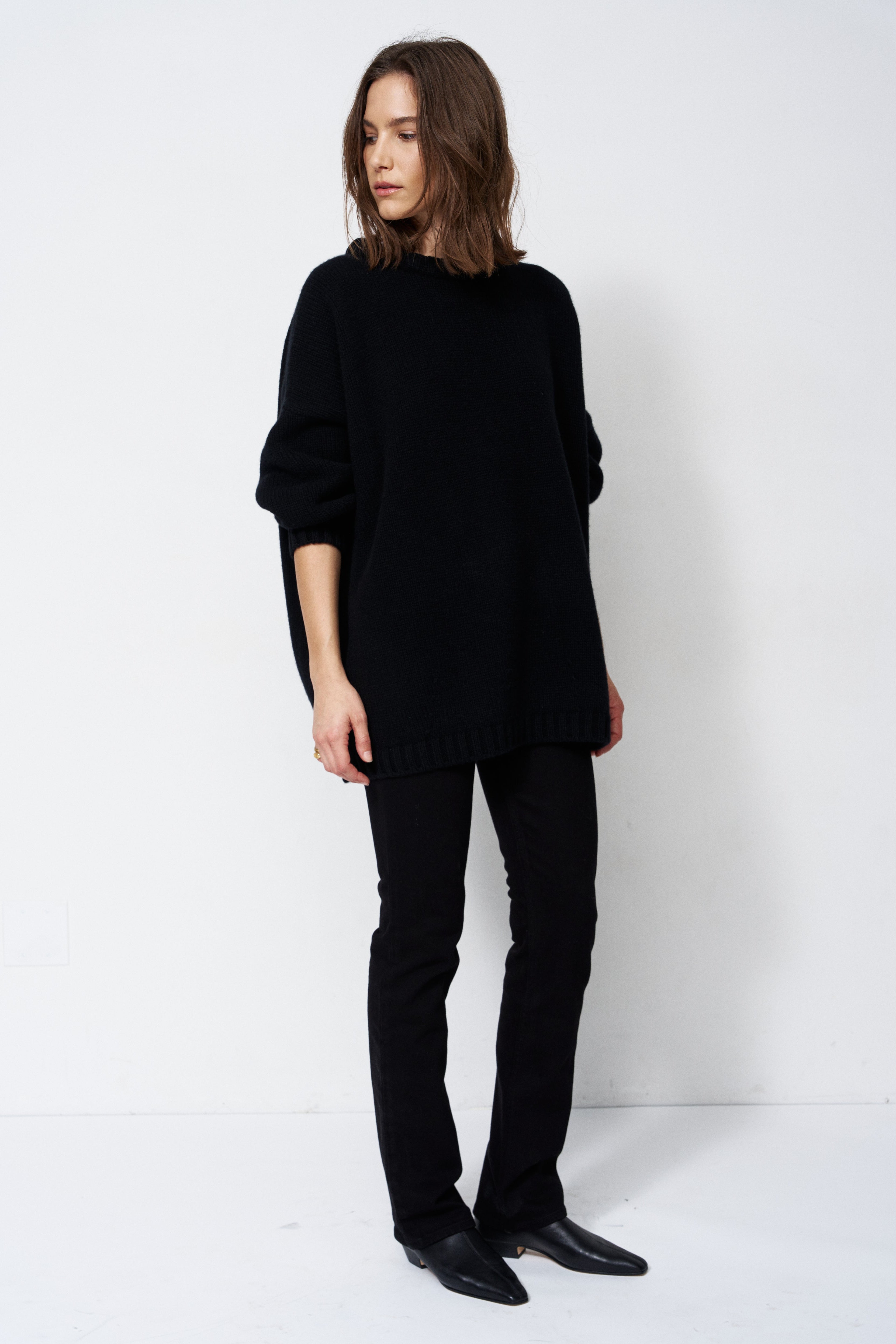 model wearing all black standing in front of a white wall