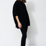 model wearing all black standing in front of a white wall