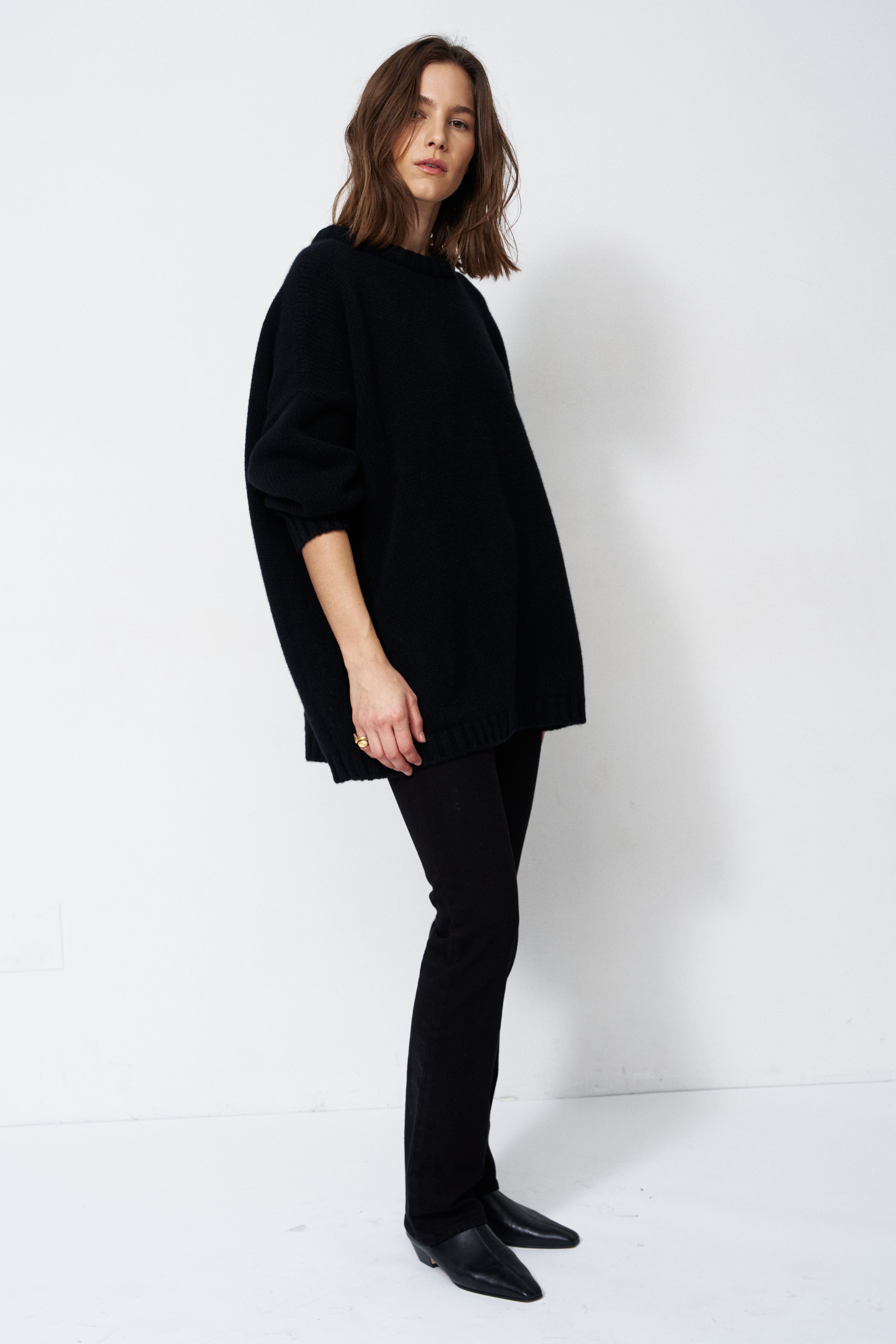model wearing all black standing in front of a white wall
