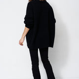 model wearing all black standing in front of a white wall