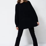 model wearing all black standing in front of a white wall