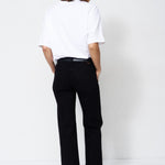 A model shown from the back wearing a white t-shirt and black wide-leg trousers, standing against a plain white studio background.
