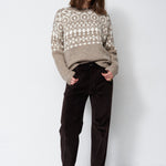 model standing with white background in grey and white sweater
