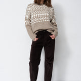 model standing with white background in grey and white sweater
