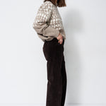 model standing in grey and white sweater with white background
