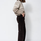 model standing in grey and white sweater with white background
