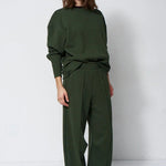 woman in green sweatsuit in front of a white wall