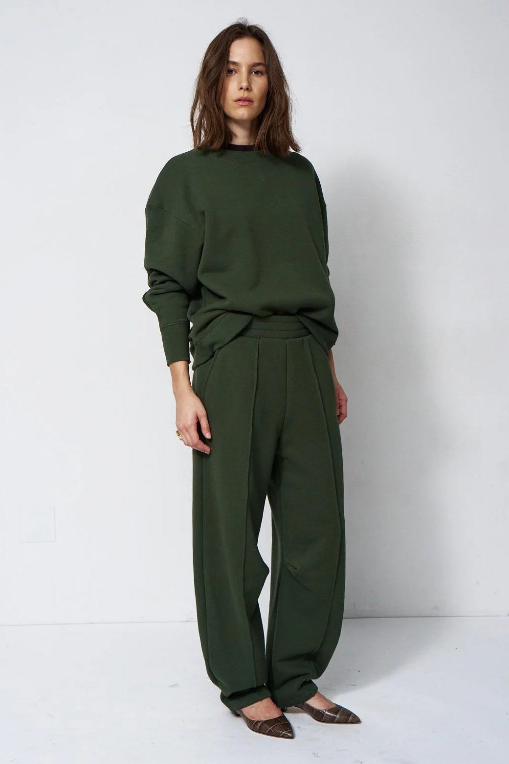 woman in green sweatsuit in front of a white wall