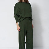 woman in green sweatsuit in front of a white wall