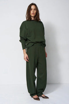 woman in green sweatsuit in front of a white wall