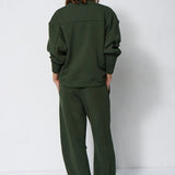 woman in green sweatsuit in front of a white wall