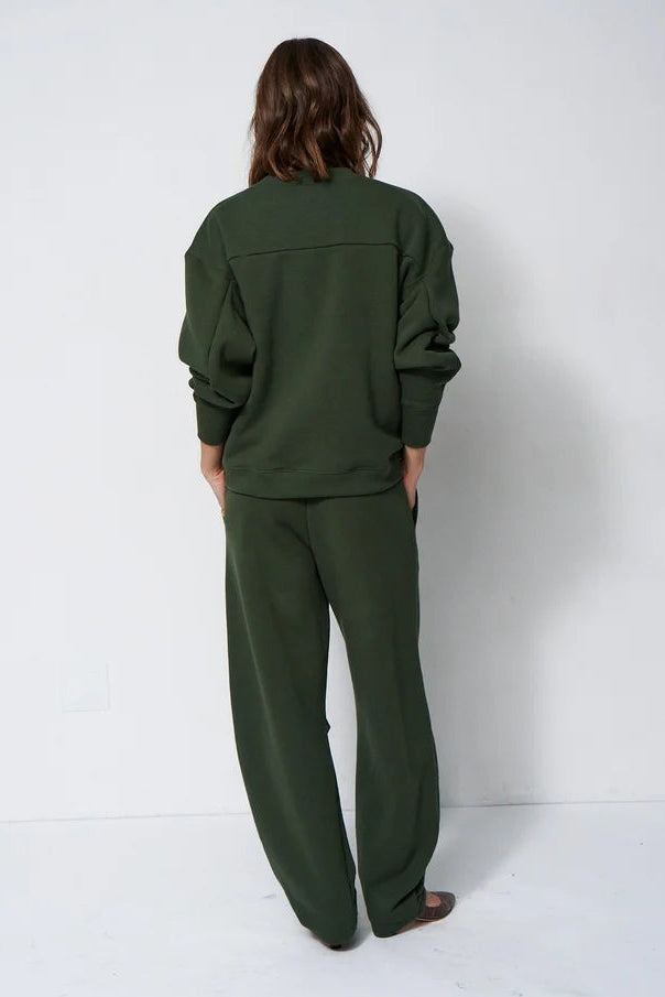 woman in green sweatsuit in front of a white wall