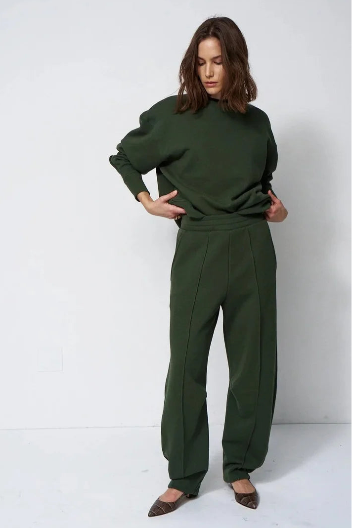 woman in green sweatsuit in front of a white wall