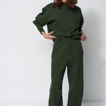 woman in green sweatsuit in front of a white wall