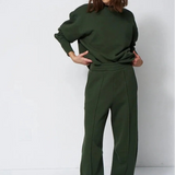 woman in green sweatsuit in front of a white wall