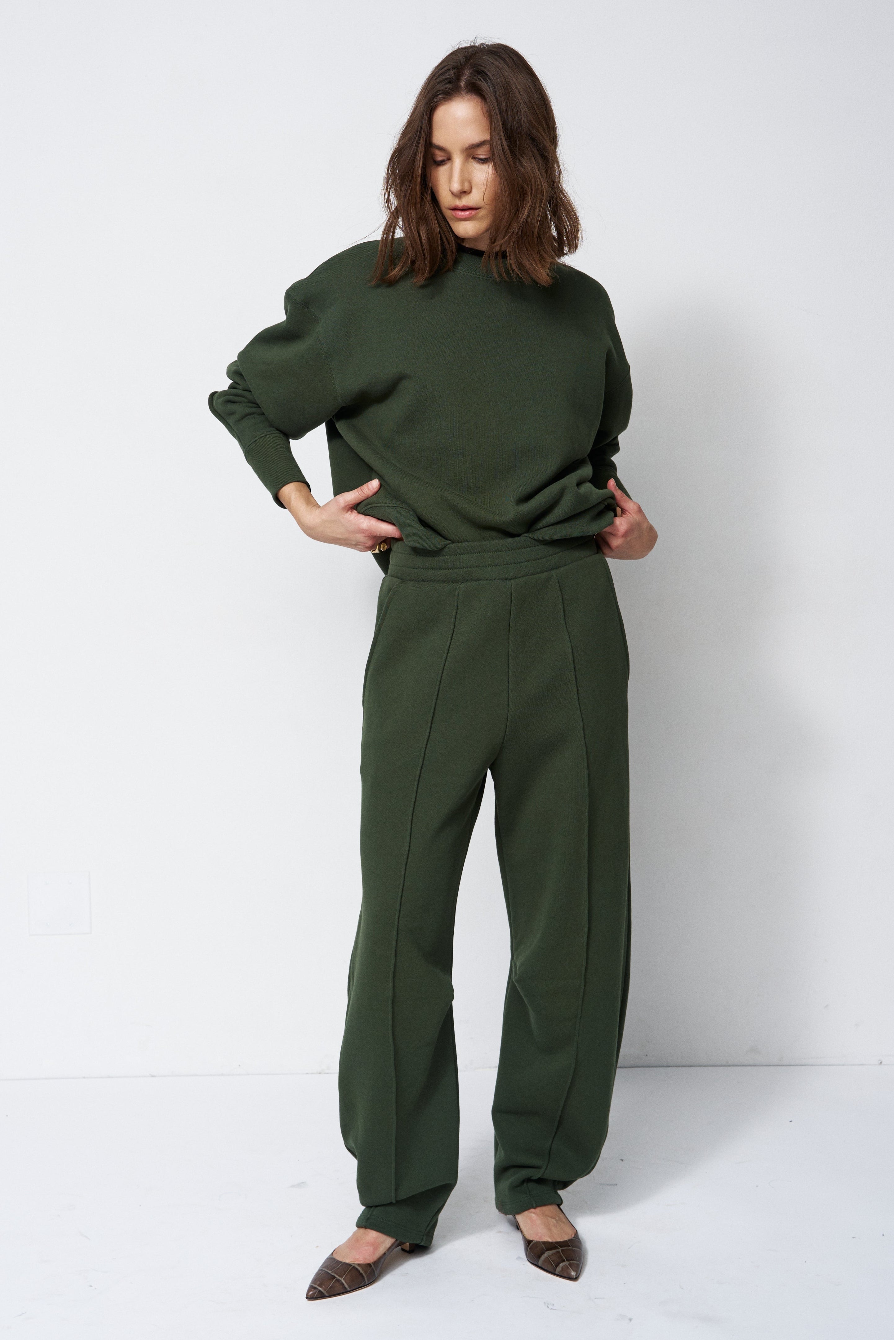 woman in all green sweatsuit standing in front of a white wall