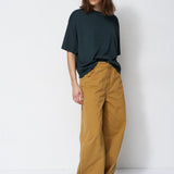 Person wearing a dark green t-shirt and mustard yellow pants against a white background
