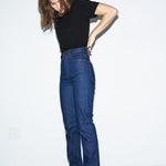 Person wearing blue jeans and a black top on a white background