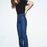 Person wearing blue jeans and a black top on a white background