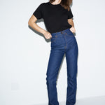 Woman wearing blue jeans and a black top on a white background