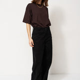 Person wearing a brown top and black pants against a white background