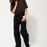 Person wearing a dark brown shirt and black pants on a white background