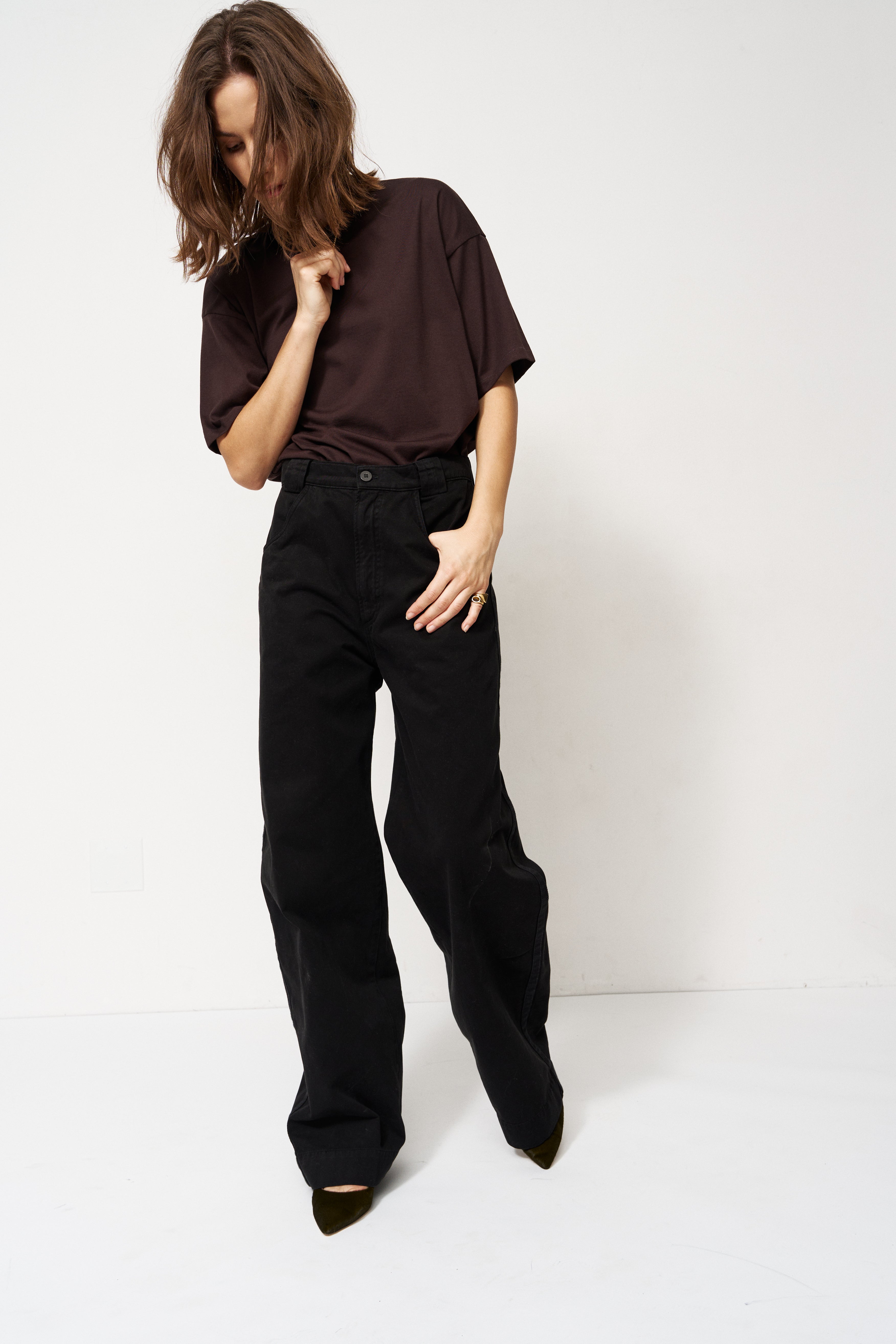 Person wearing a dark brown shirt and black pants on a white background