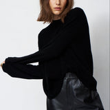 A woman modeling a black long-sleeve knit top with a relaxed, slightly oversized fit, paired with black leather pants, against a plain light gray studio background.