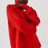 A model wearing a bright red knit sweater and matching red trousers, shown from the side against a plain light gray studio background.
