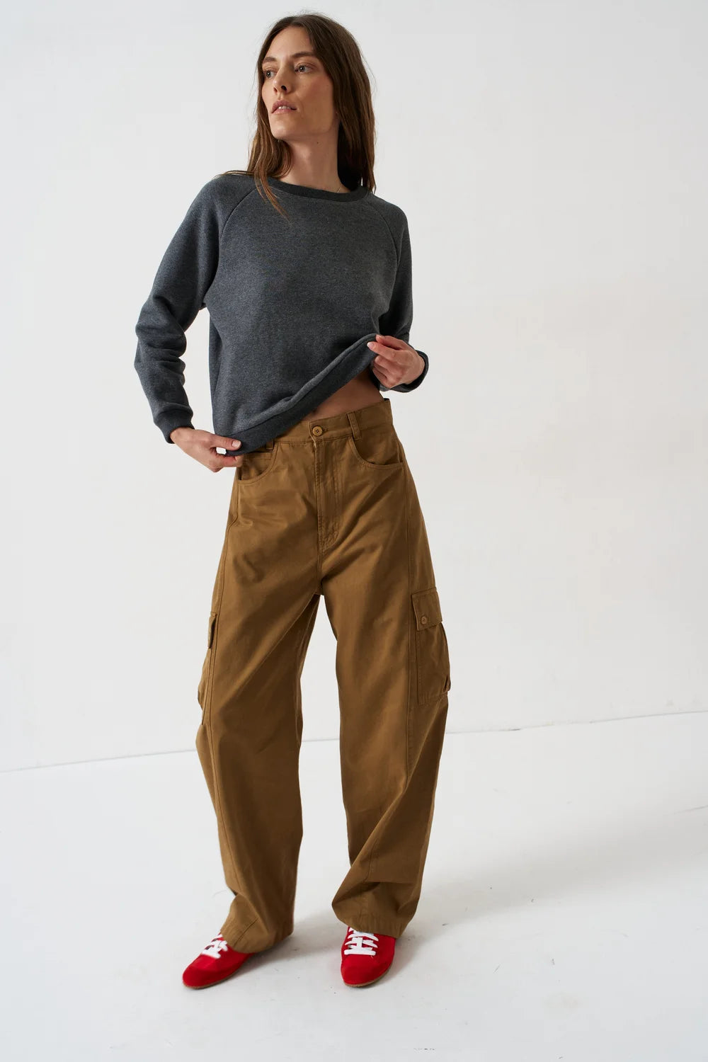 Woman wearing a Jamie Haller Deep Grey Daily Sweatshirt, brown cargo pants, and red sneakers.