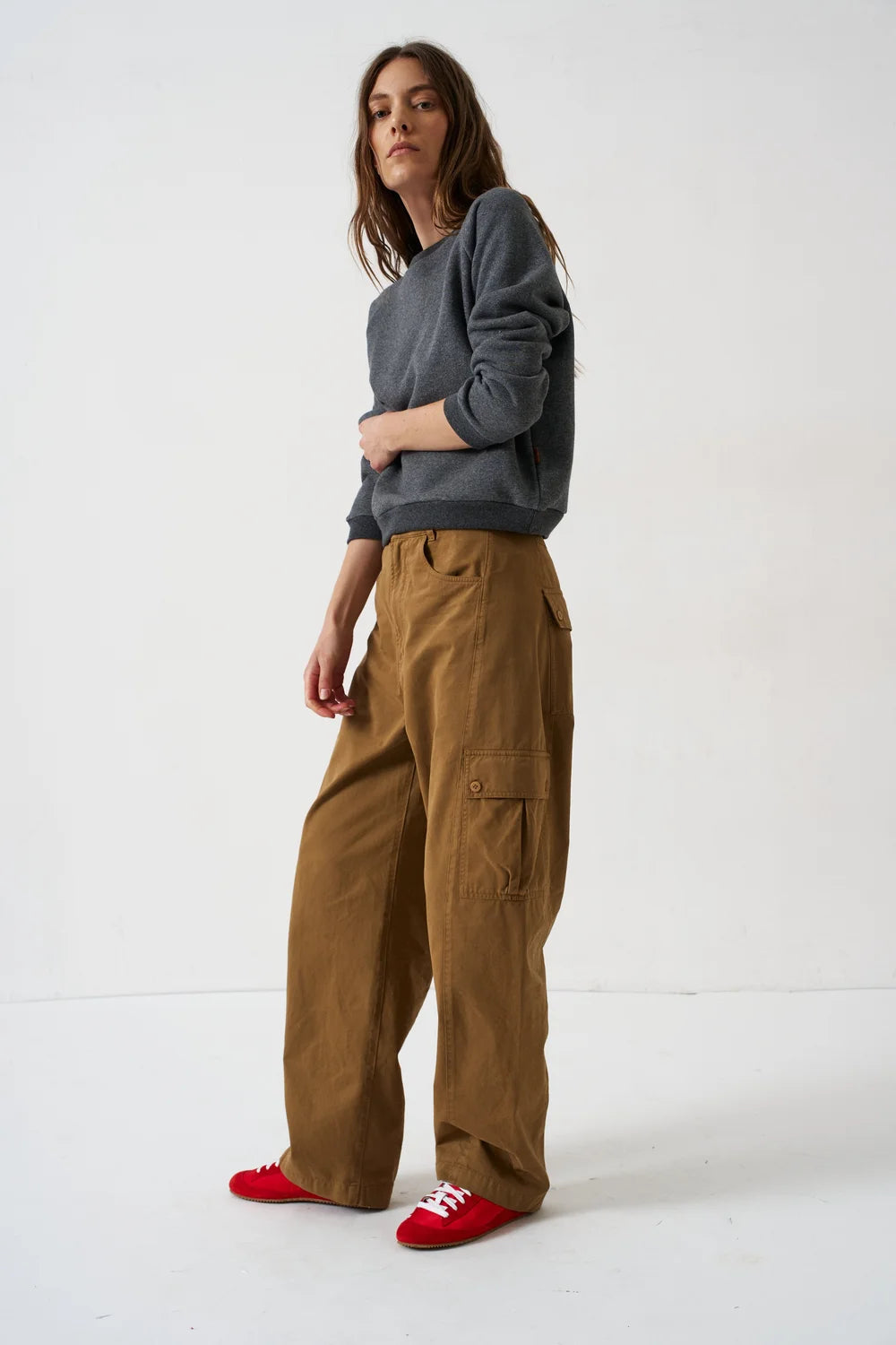 Woman wearing Jamie Haller deep grey sweatshirt, brown cargo pants, and red sneakers.