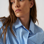 Woman wearing a blue striped shirt against a white background