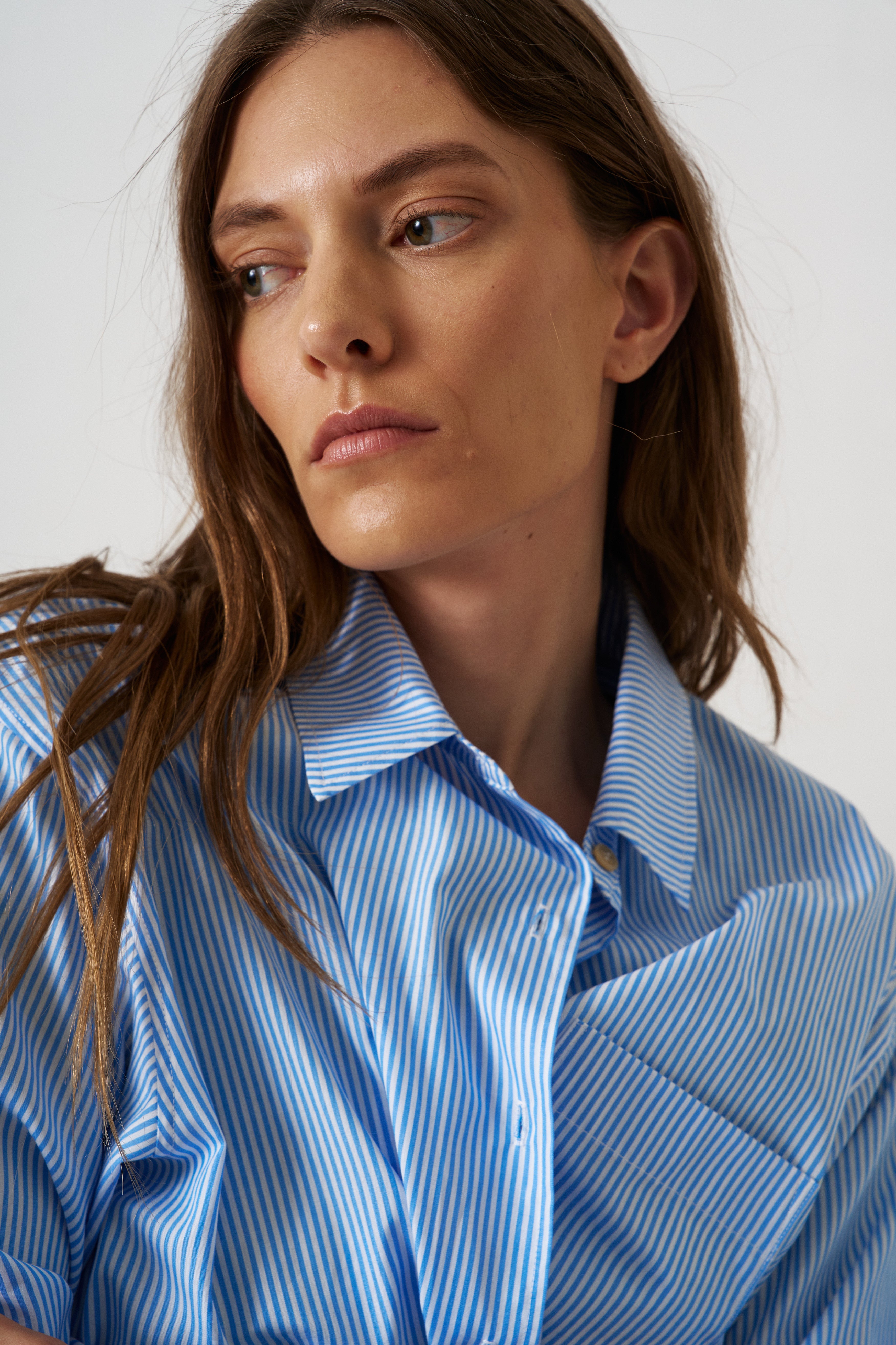 Woman wearing a blue striped shirt against a white background