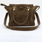 A dark brown suede handbag with gold-tone hardware and a matching shoulder strap, displayed against a clean white background.