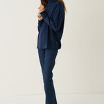 A woman modeling a navy blue long-sleeve top and matching navy blue jeans against a plain off-white studio background.