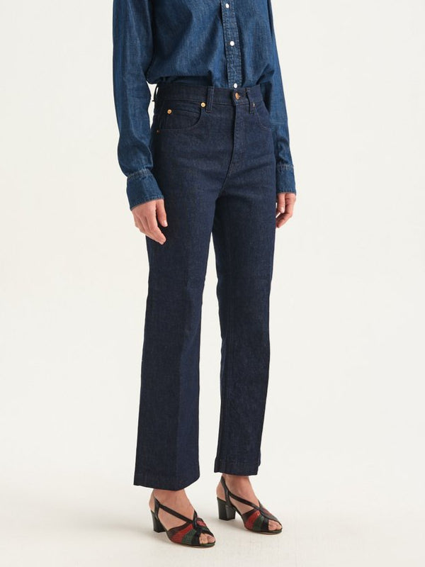 Person wearing a blue denim shirt and dark blue jeans on a white background