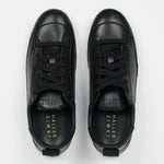 A pair of black leather low-top sneakers shown from a top-down view on a light gray background. The brand name 'JAMIE HALLER' is printed in gold on the black insoles.