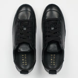 A pair of black leather low-top sneakers shown from a top-down view on a light gray background. The brand name 'JAMIE HALLER' is printed in gold on the black insoles.