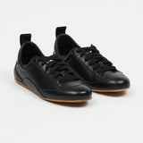 black leather sneakers set in front of white wall
