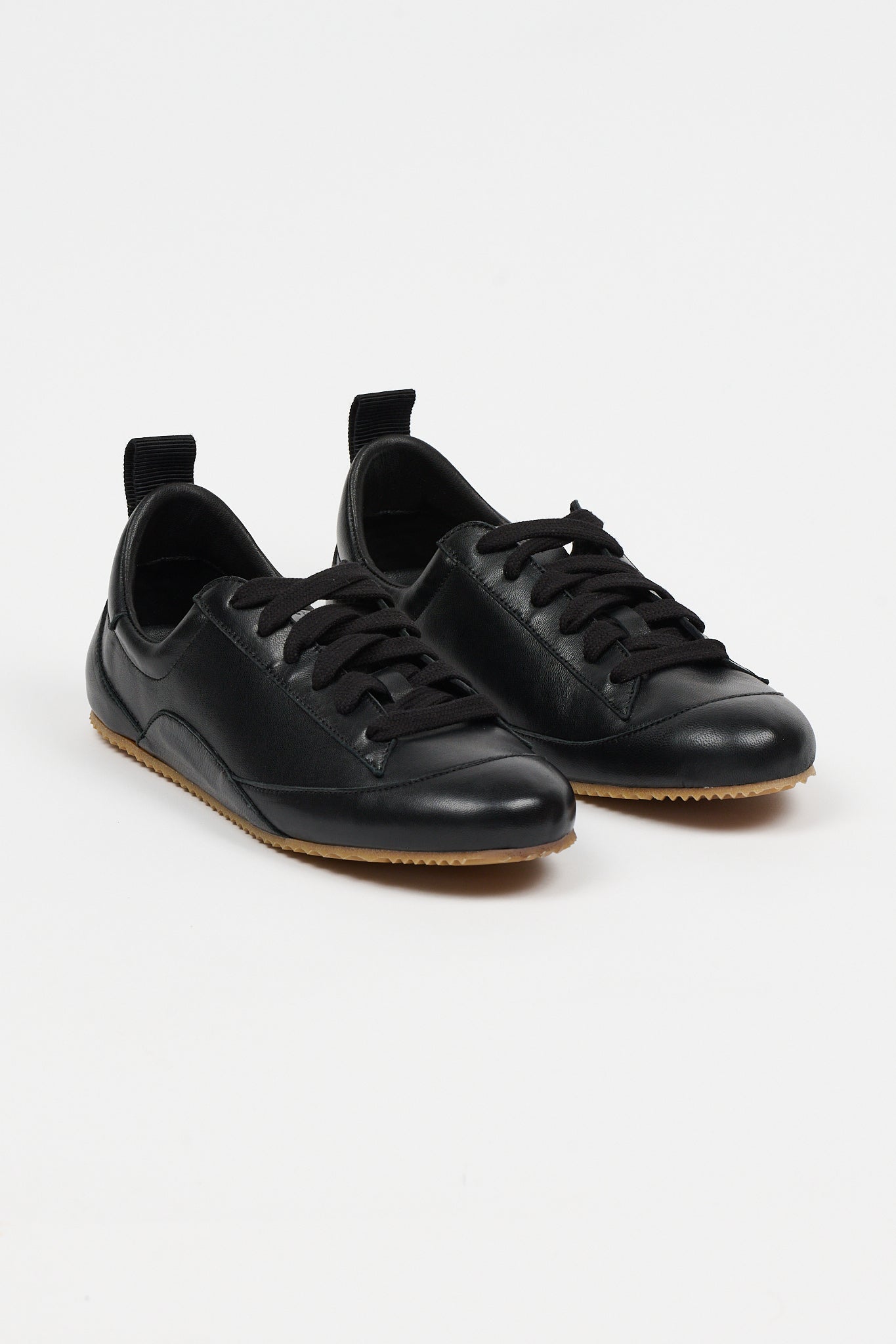 black leather sneakers set in front of white wall
