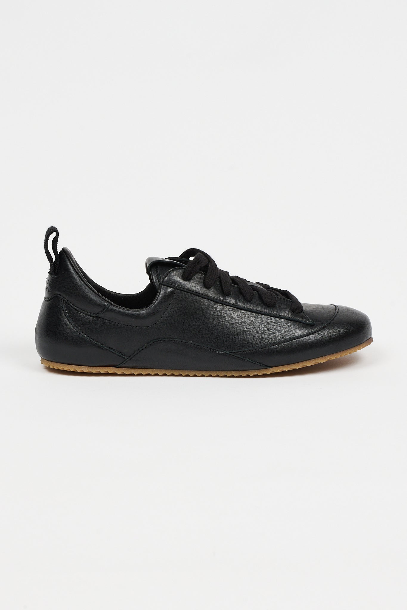 one black leather sneaker in front of white background