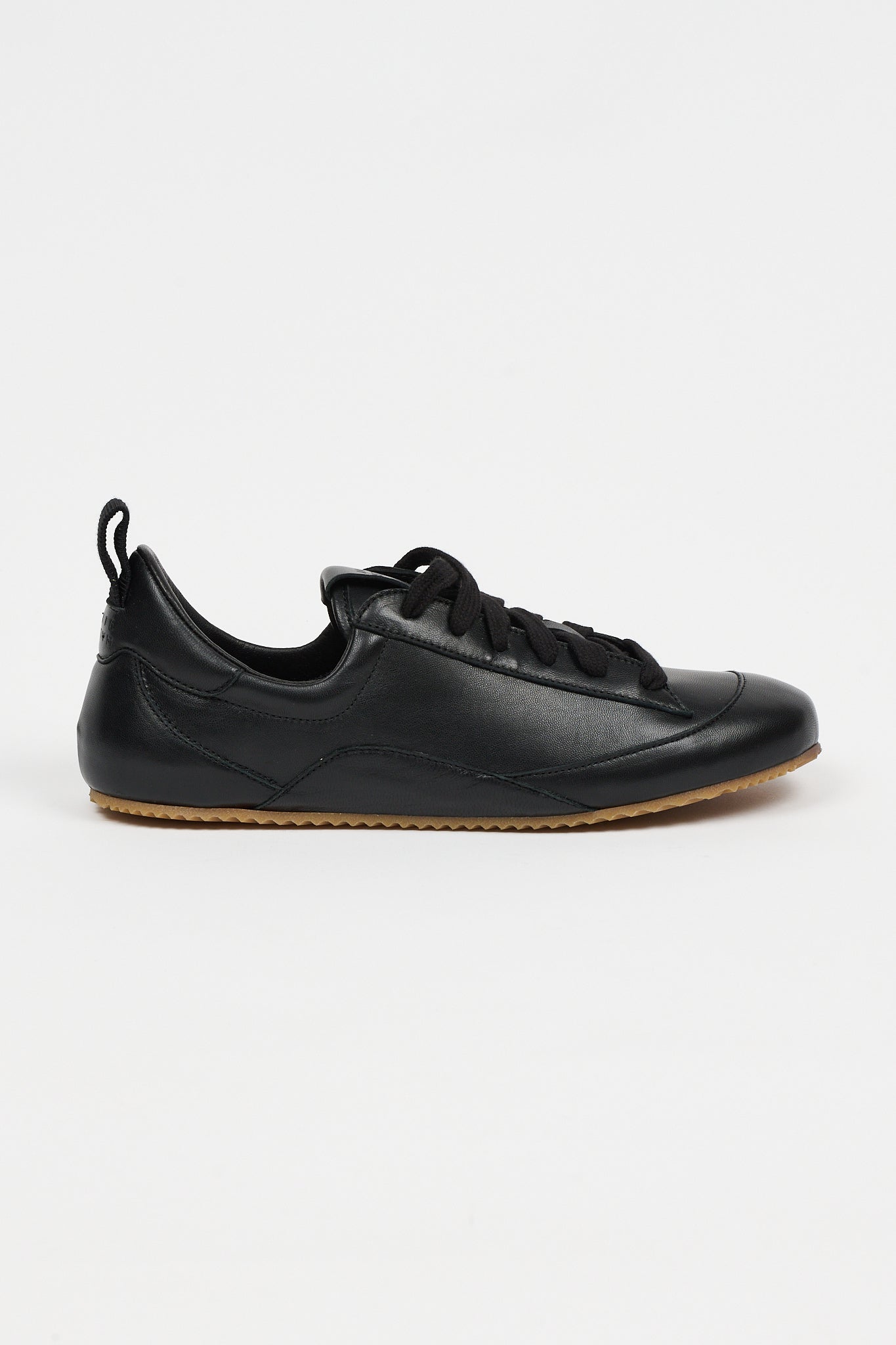 one black leather sneaker in front of white background