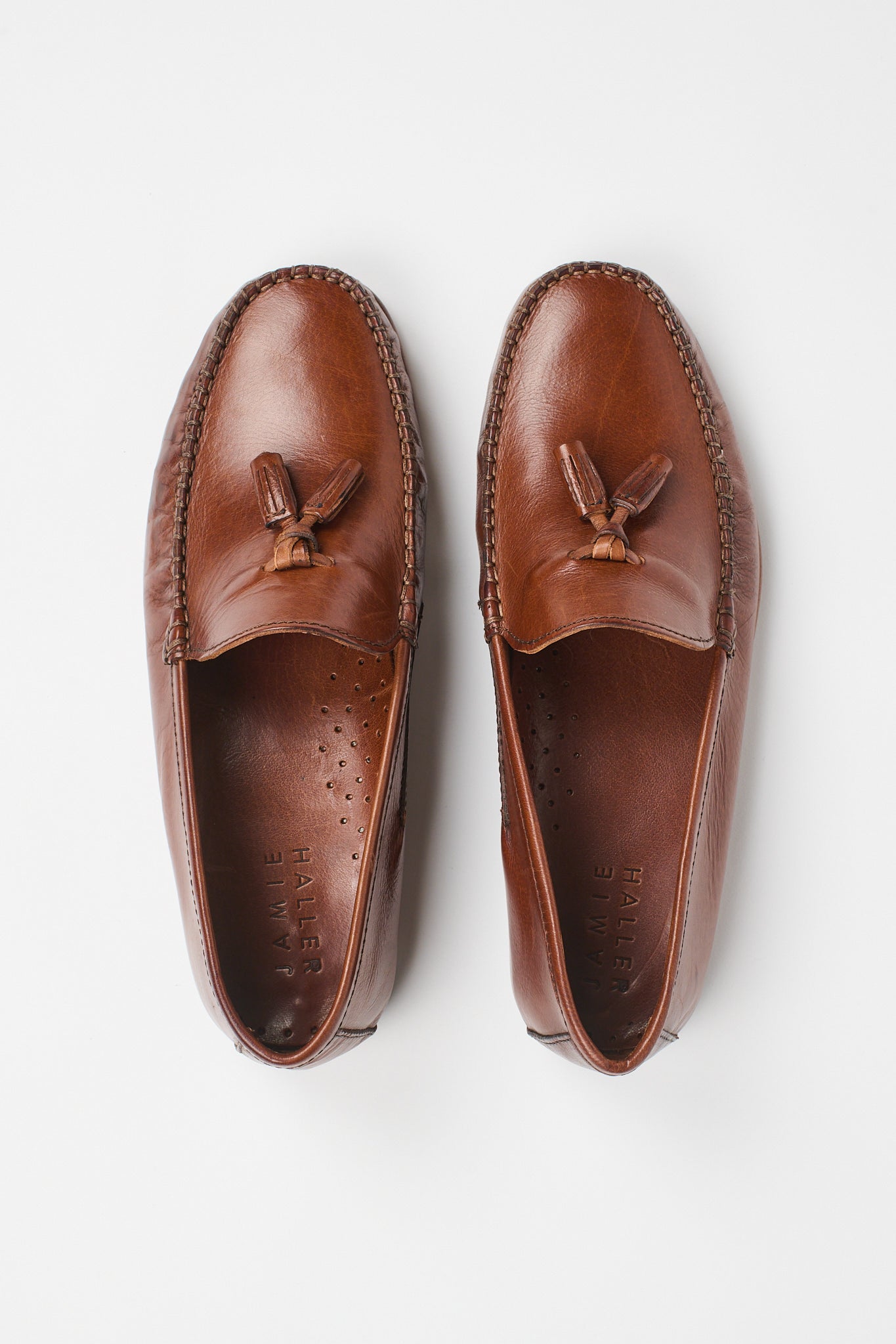 A pair of brown leather tassel loafers shown from a top-down view on a clean white background.