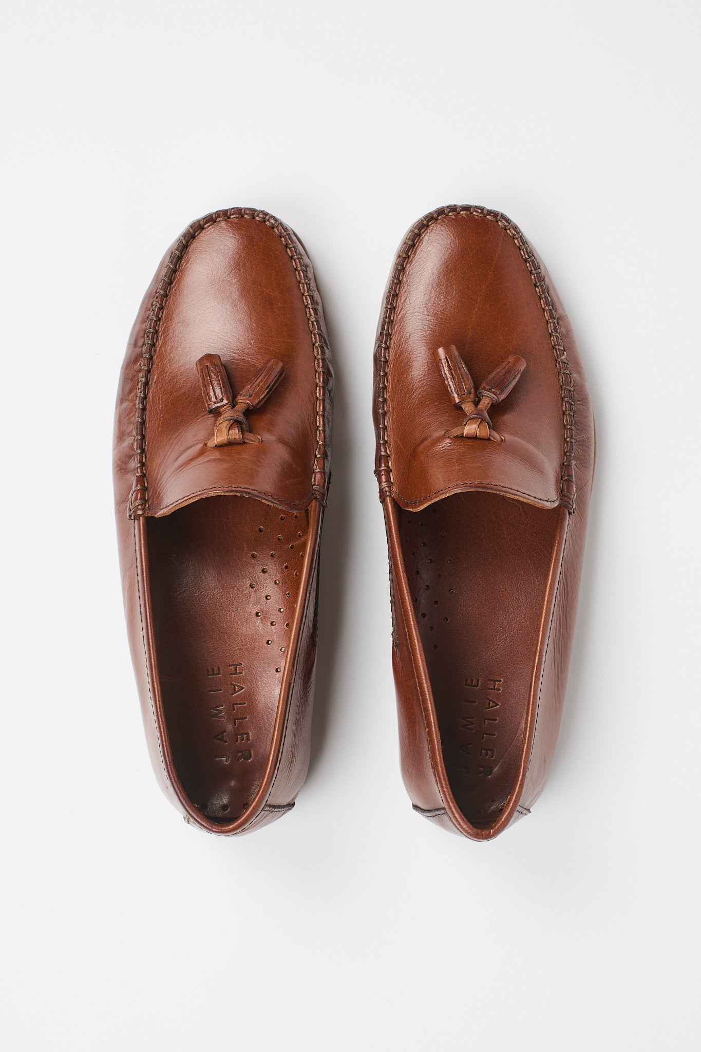 A pair of brown leather tassel loafers shown from a top-down view on a clean white background.