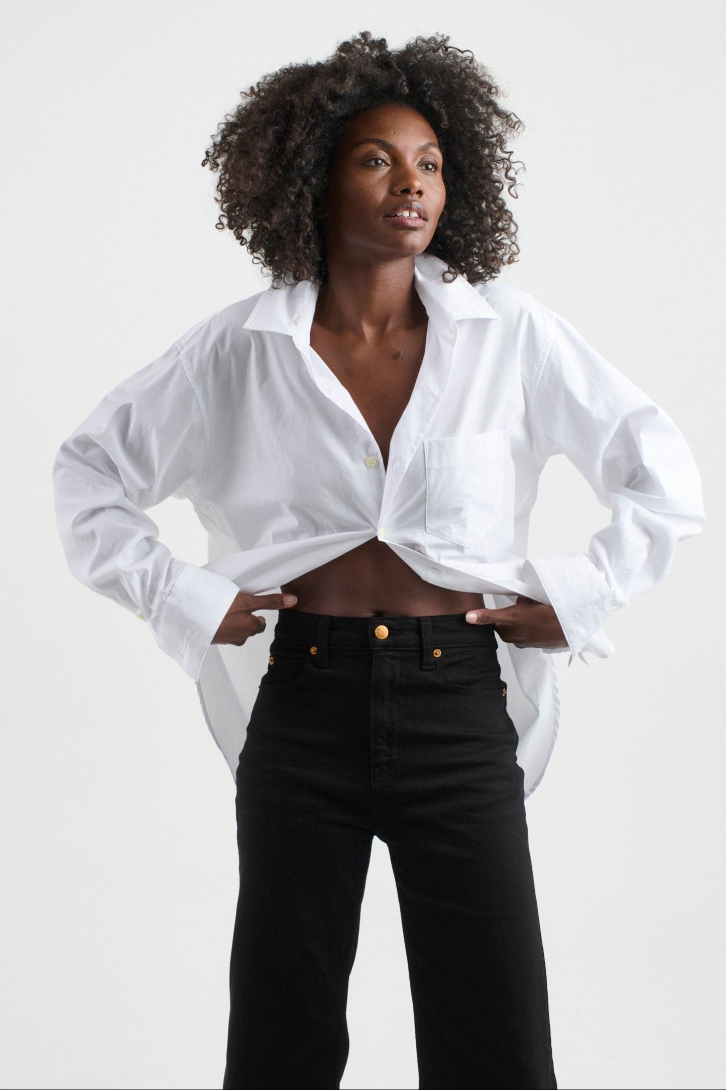 a person wearing a white blouse and black jeans with a white background. 