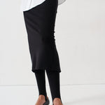 legs of a woman in white blouse, black skirt, and black heels