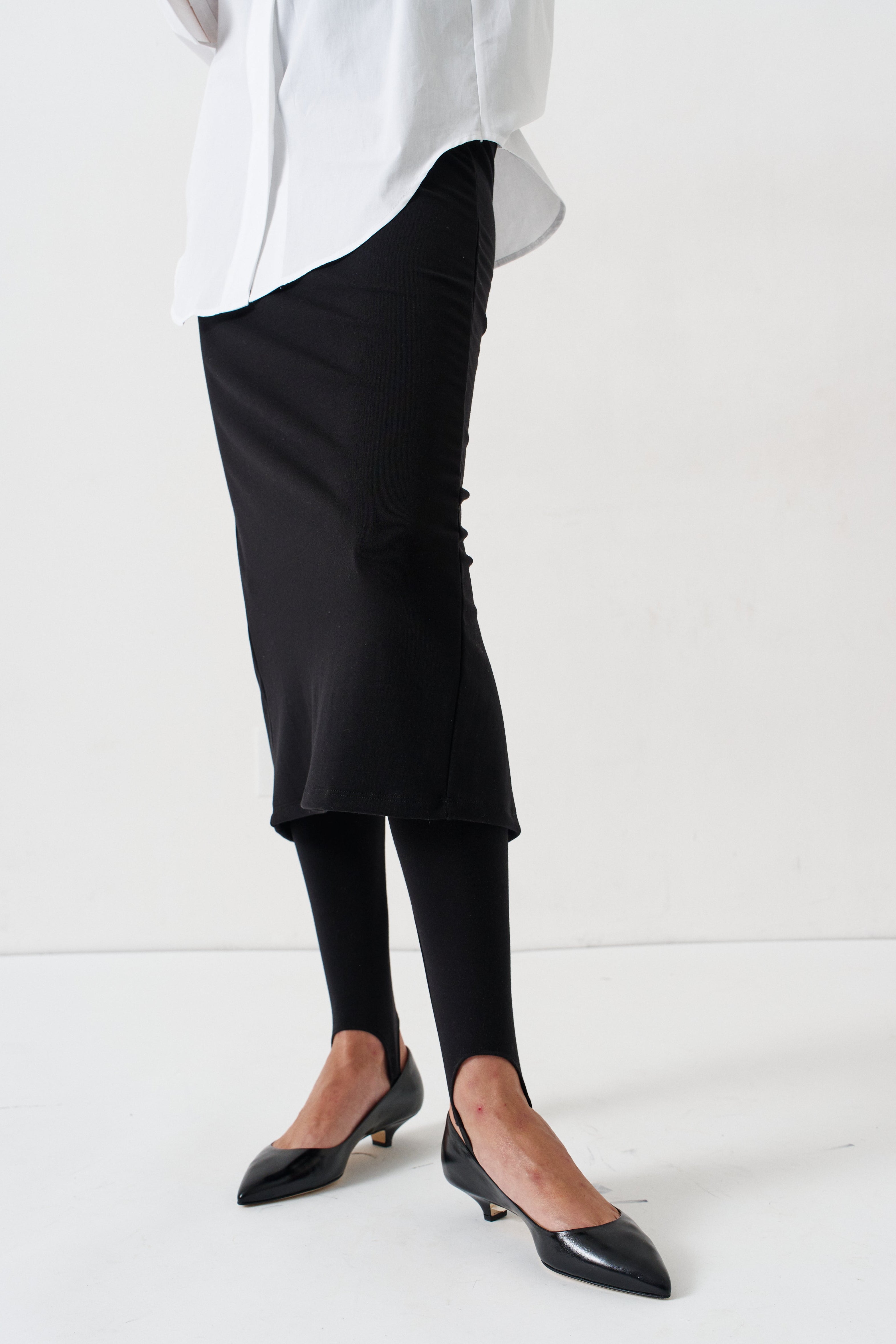 legs of a woman in white blouse, black skirt, and black heels