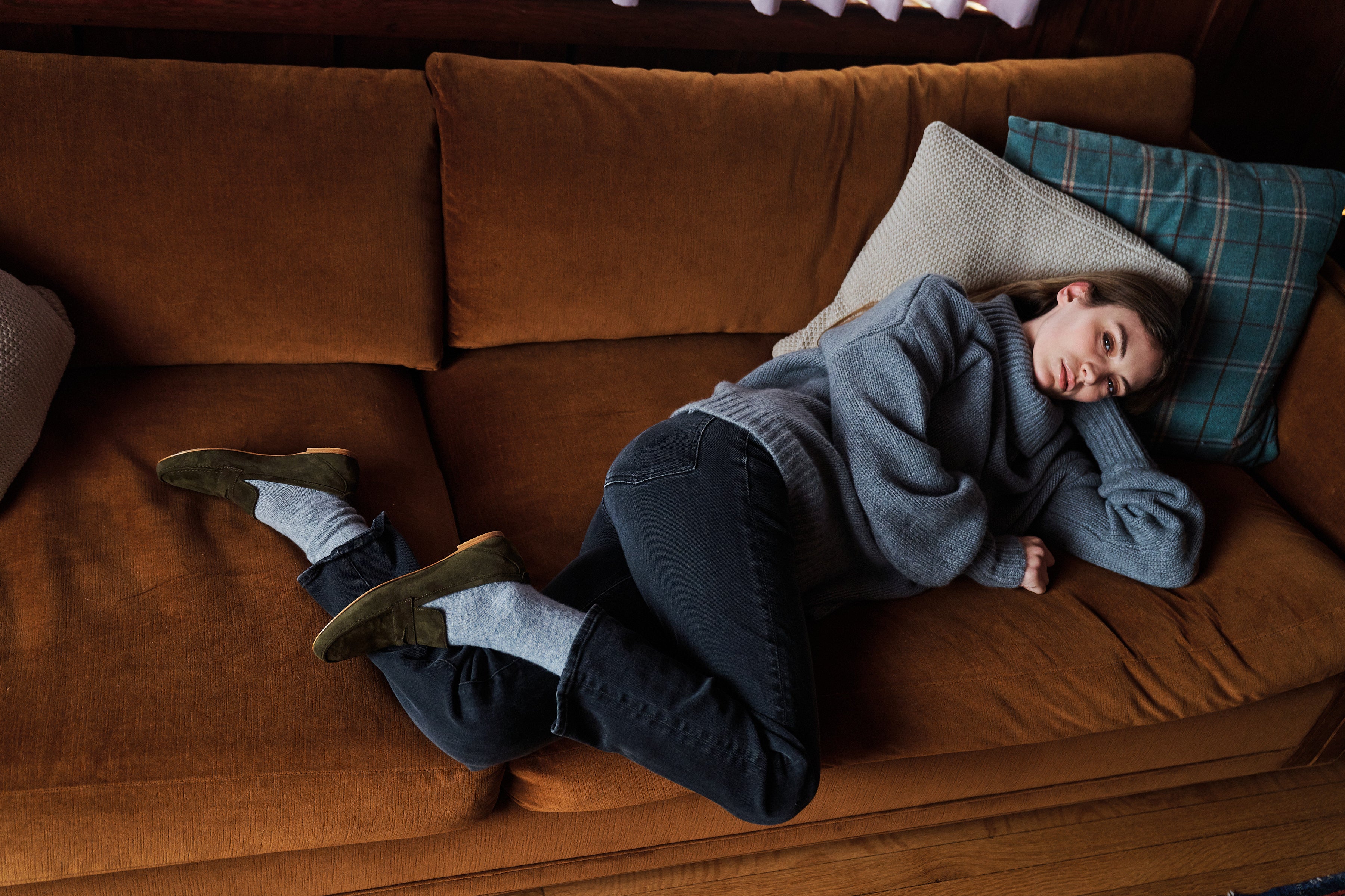 Woman laying on couch, side view of olive suede loafers