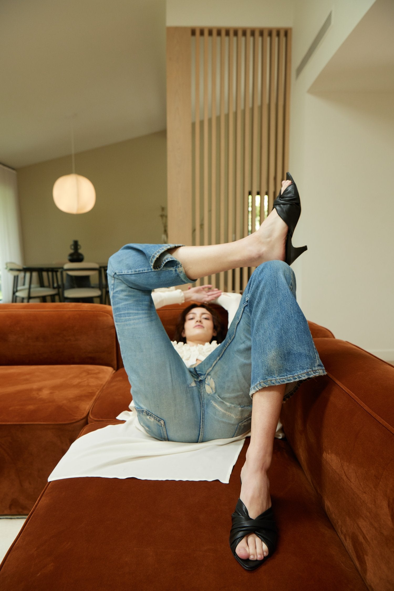 Woman laying on couch with legs bent, knot heel in black