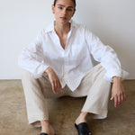 Person wearing a white shirt and beige pants sitting on a concrete floor.